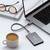 Laptop mit externer Festplatte verbunden, daneben eine Kaffeetasse und eine Brille. Büroarbeitsplatz-Szene mit stilvollem Zubehör.