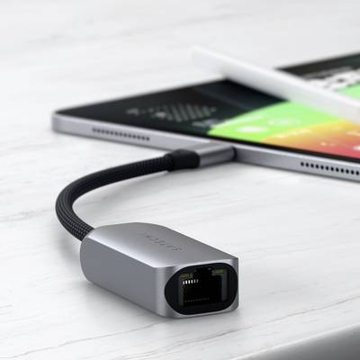 Ein Netzwerkkabeladapter liegt auf einem Tisch neben einem Tablet. Der Adapter hat einen Ethernet-Anschluss und ein kurzes, geflochtenes Kabel.