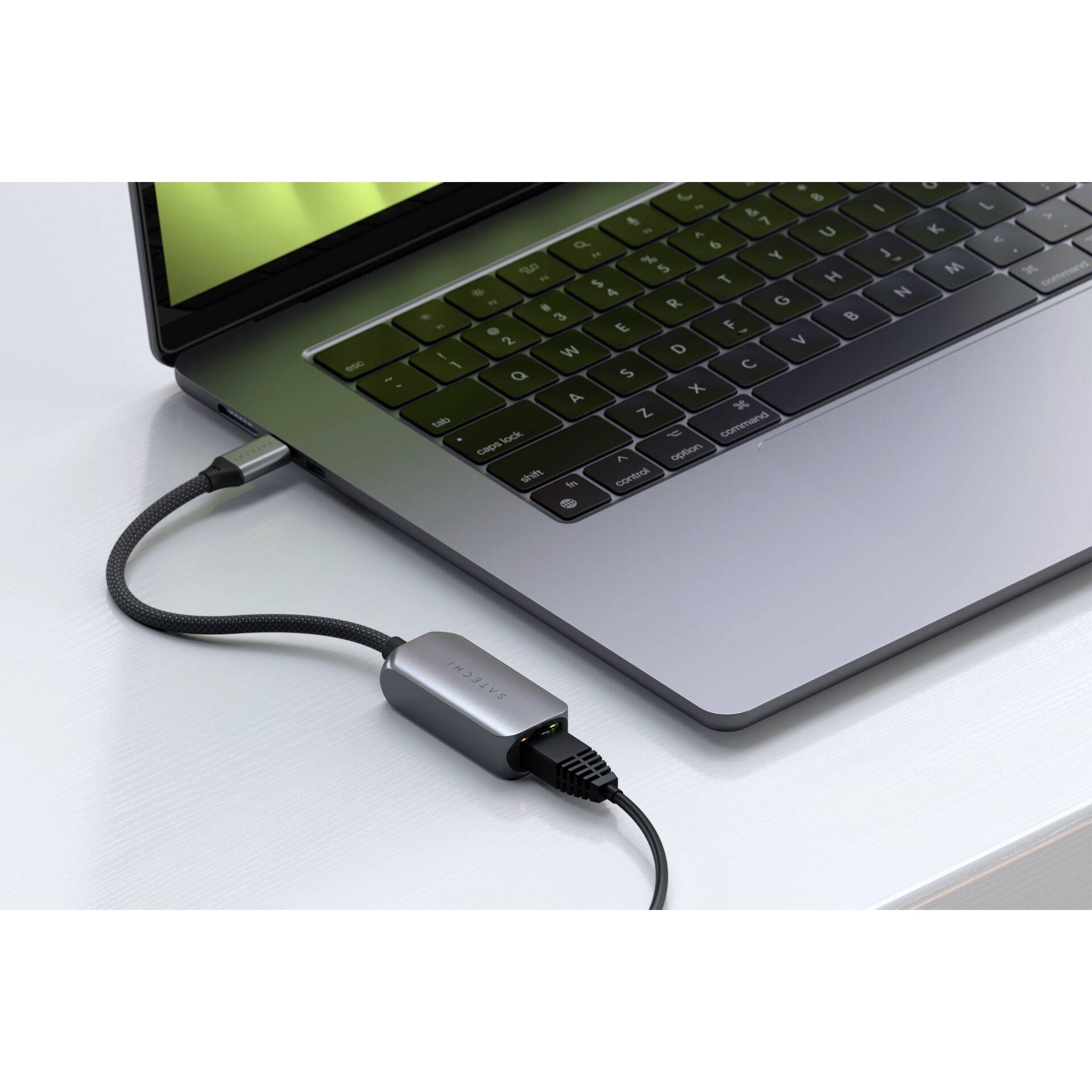 Ein Laptop ist über ein geflochtenes Kabel und einen Adapter mit einem anderen Gerät verbunden. Der Bildschirm zeigt schwache Reflexionen.