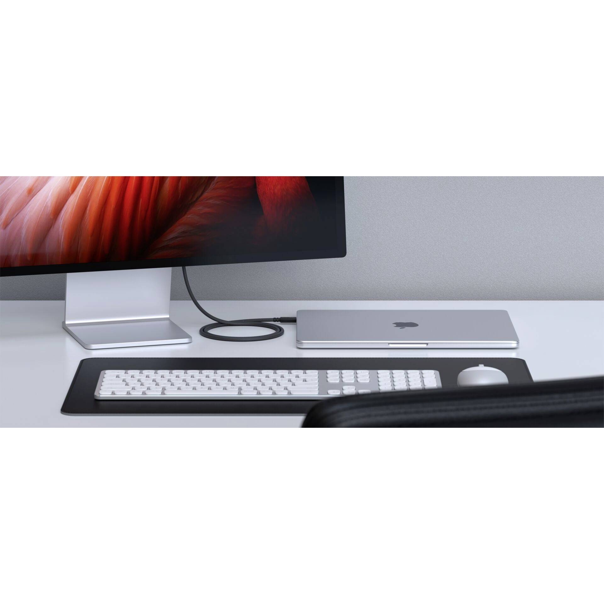 'Schreibtisch mit Monitor, geschlossener Laptop, Tastatur und Maus. Der Bildschirm zeigt ein abstraktes rotes Design.'