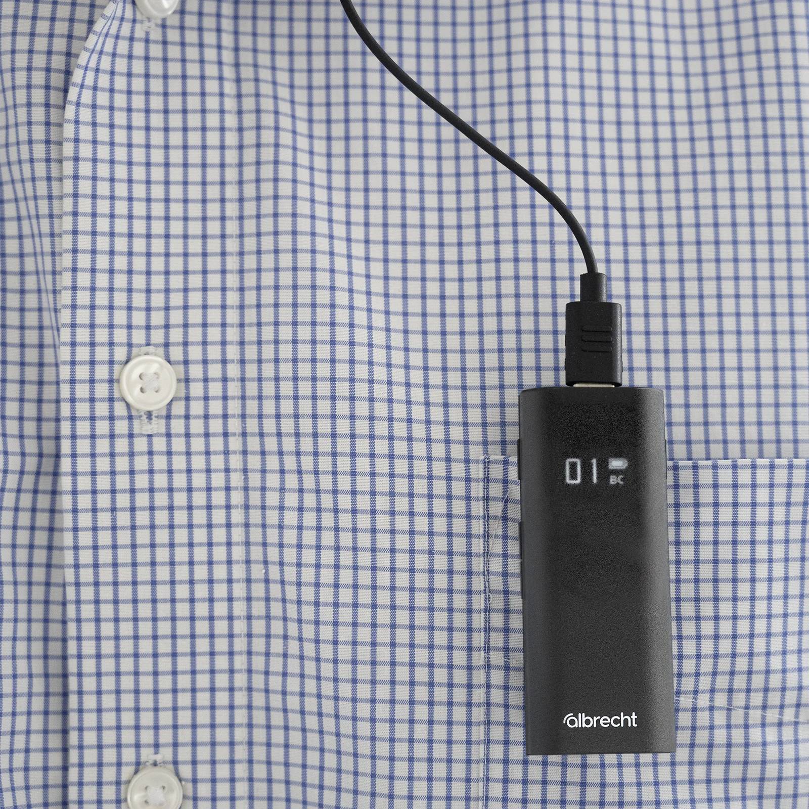 Ein Kastenförmiges Gerät hängt an einem karierten Hemd. Das Display zeigt '01 BC'. Das Gerät ist mit einem Kabel verbunden.