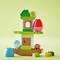 Ein bunter Turm aus LEGO-Duplo-Steinen mit Figuren und Türen, aufgebaut in fröhlichen Farben auf hellgrünen Hintergrund.