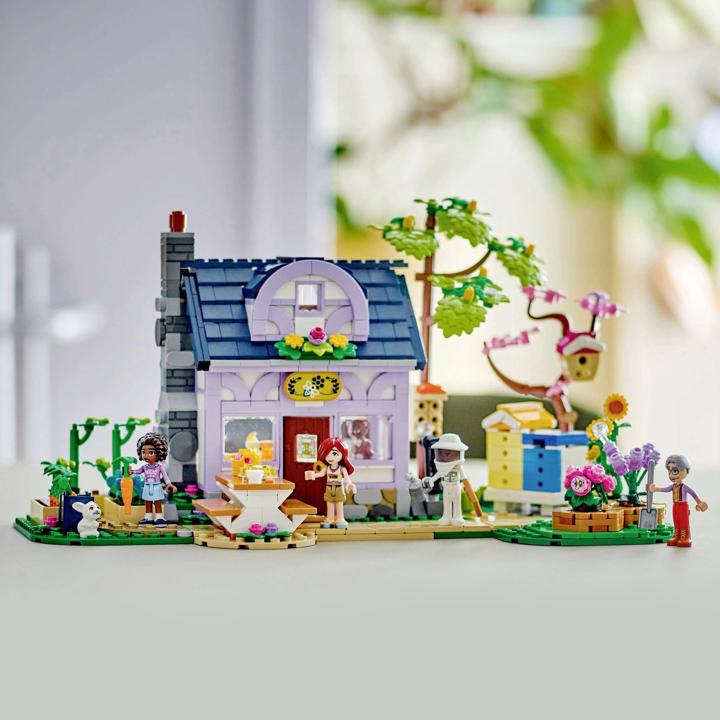Ein farbenfrohes LEGO-Haus mit Garten und Figuren, umgeben von Pflanzen und Detailgegenständen, dargestellt in einer wohnlichen Szene.