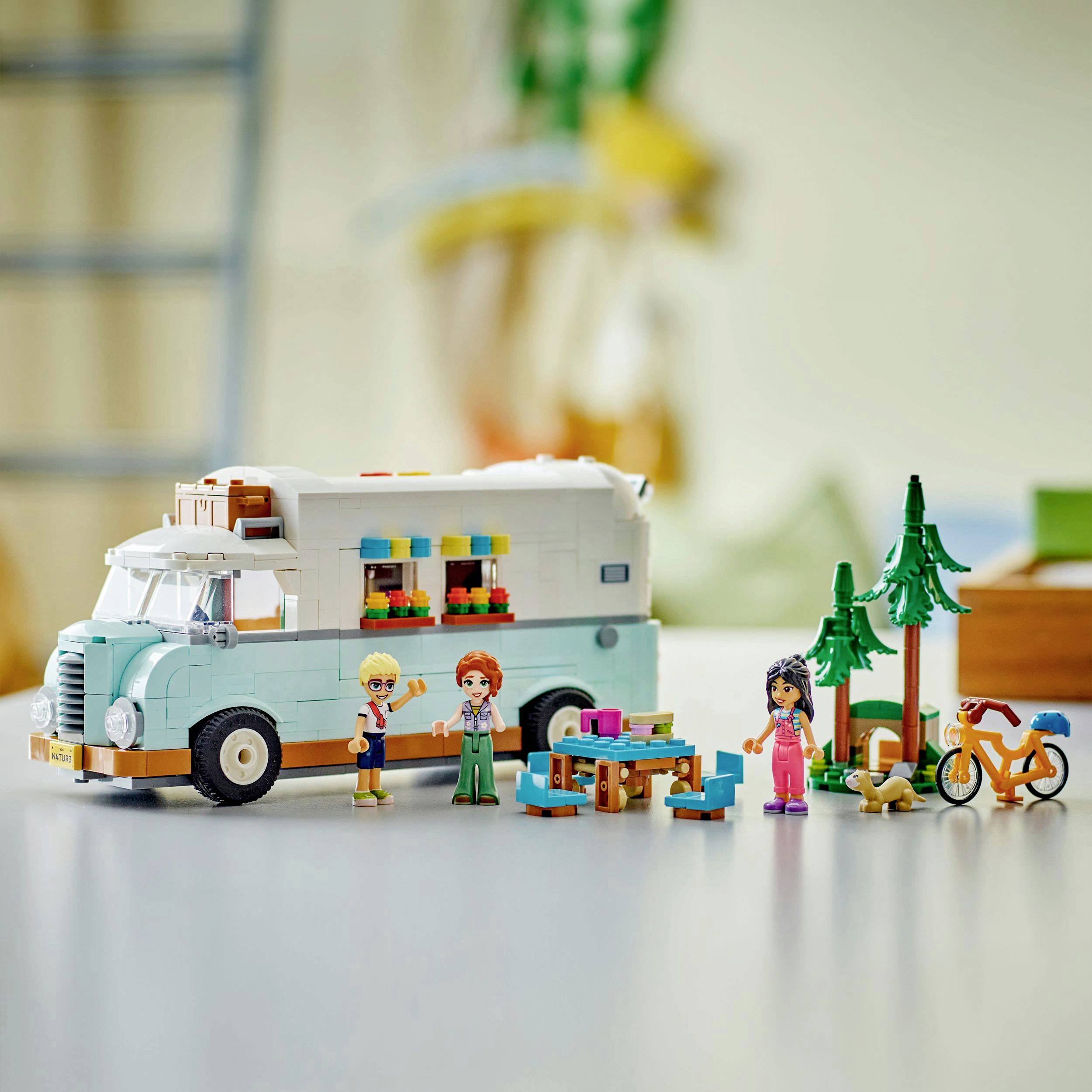 Ein farbenfrohes Wohnmobil-Spielzeugset mit Spielfiguren, einem Tisch, Bäumen und einem Fahrrad. Szenario eines Camper-Abenteuers.