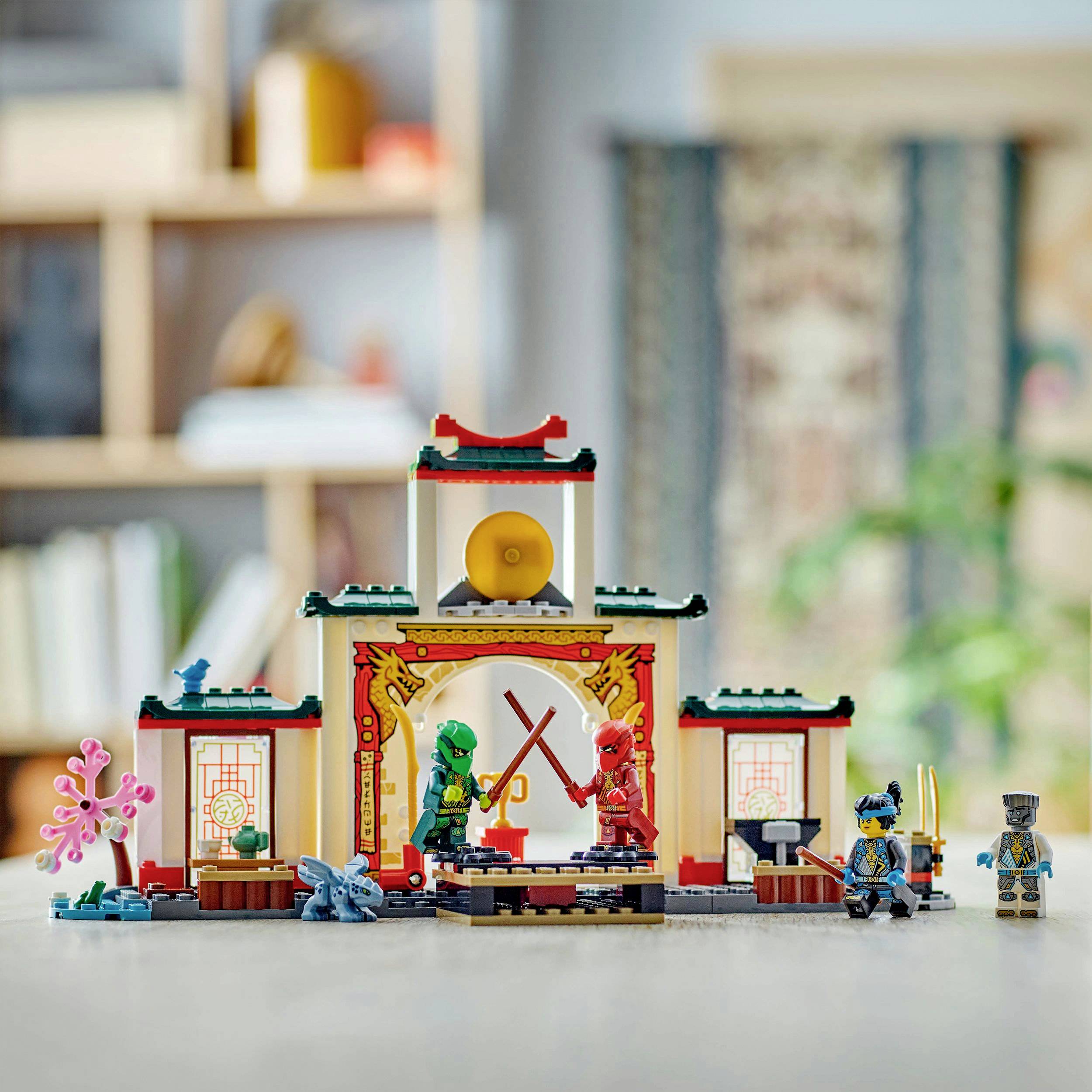 Zwei LEGO-Ninja-Figuren kämpfen in einem asiatisch inspirierten Tempel-Set mit einer kleinen goldenen Glocke im Hintergrund.