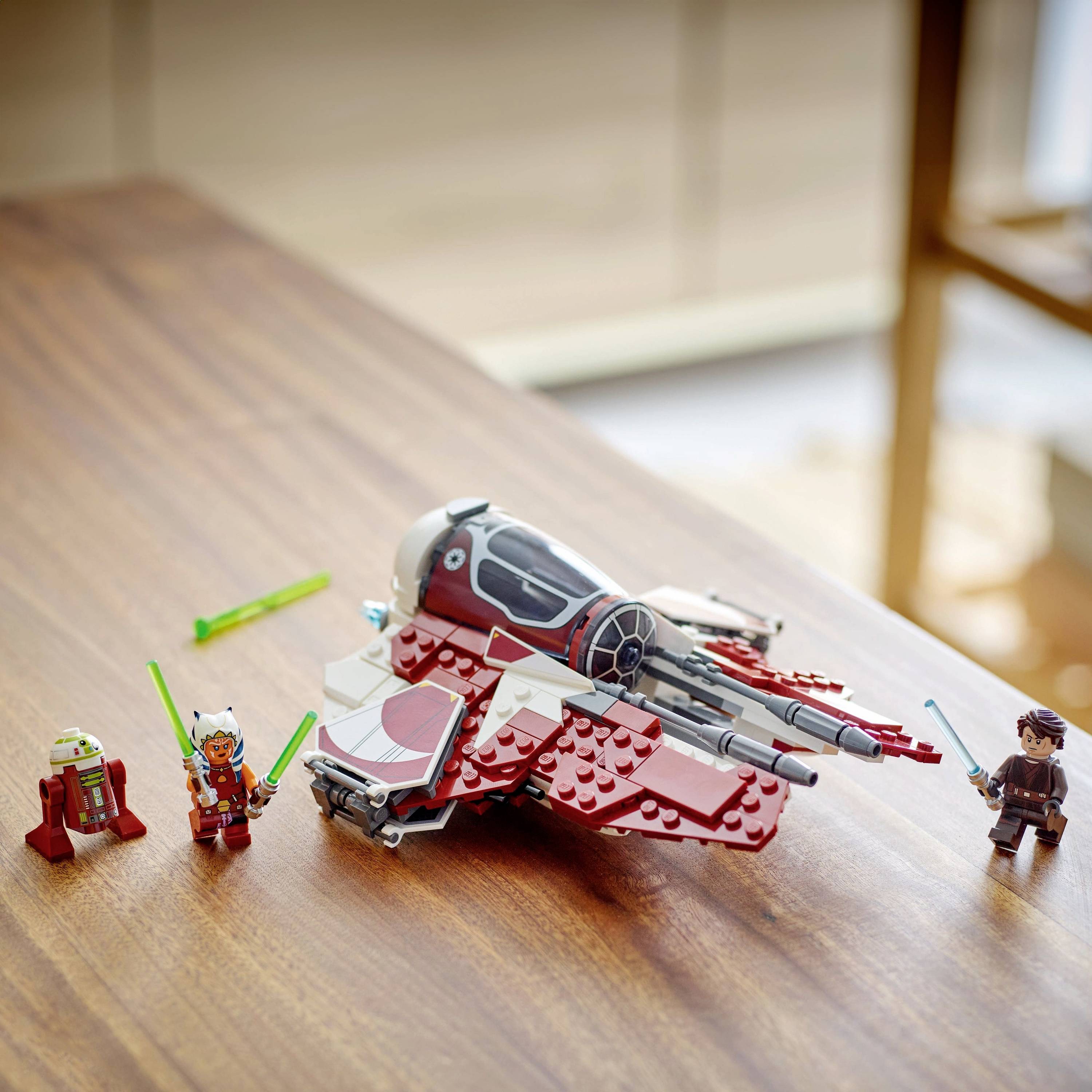 Ein Spielzeug-Raumschiff mit zwei Actionfiguren und einem Roboter auf einem Tisch. Die Figuren halten bunte Lichtschwerter.