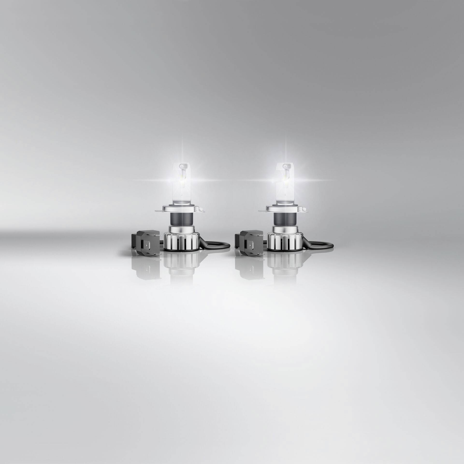 Zwei LED-Lampen auf einer glatten Oberfläche leuchten, umgeben von einem schlichten grauen Hintergrund. Ideal für moderne Beleuchtung.