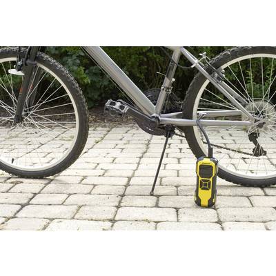 Ein schwarzes Fahrrad auf Kopfsteinpflaster steht neben einer gelben tragbaren Luftpumpe. Das Fahrrad ist unbenutzt und die Pumpe bereit.