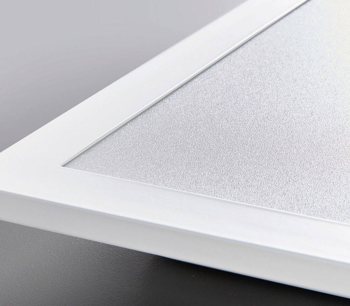 Ecke eines silbernen Bilderrahmens mit glatter, rechteckiger Form, ausgelegt auf einer grauen Oberfläche.