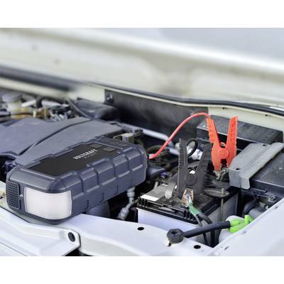 Ein Starthilfegerät ist an eine Autobatterie angeschlossen, um Strom zu liefern. Rotes und schwarzes Kabel sind an den Batteriepolen befestigt.