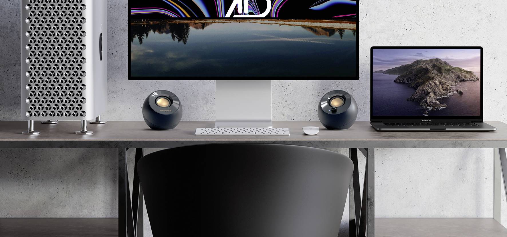 Ein moderner Schreibtisch mit einem großen Monitor, einem Computergehäuse, einem Laptop und Lautsprechern. Fokus liegt auf Technik.