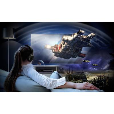 Person auf Sofa betrachtet Film mit Raumschiffen auf großem Bildschirm, trägt Kopfhörer, futuristische Szenerie mit Weltraum und Planeten.