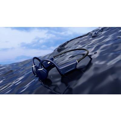 Dunkelblaue kabellose Kopfhörer liegen auf einer glänzenden, flüssigkeitsähnlichen Oberfläche im Freien unter einem blauen Himmel.