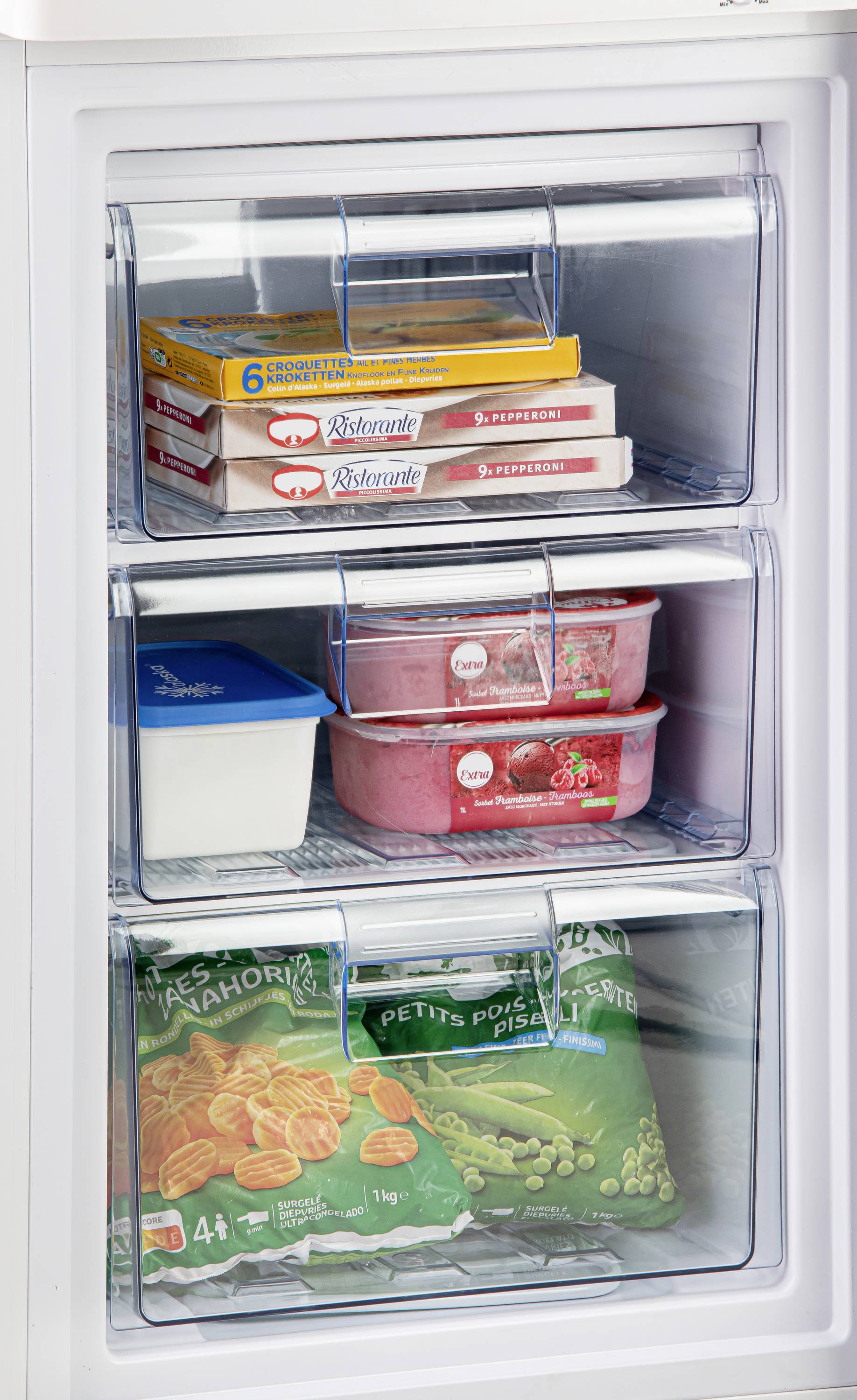 Ein geöffneter Gefrierschrank mit drei Fächern. Oben Pizzen, in der Mitte Eiscreme, unten gefrorenes Gemüse und Pommes frites in Tüten.