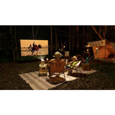 Zwei Personen sitzen abends im Wald auf Liegestühlen und schauen einen Film, der mit einem Projektor auf eine Leinwand projiziert wird.
