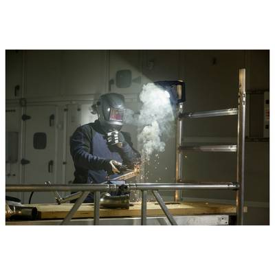 Ein Arbeiter mit Schweißhelm schweißt Metall in einer Industriewerkstatt, wobei helle Funken und Rauch um das Werkstück aufsteigen.