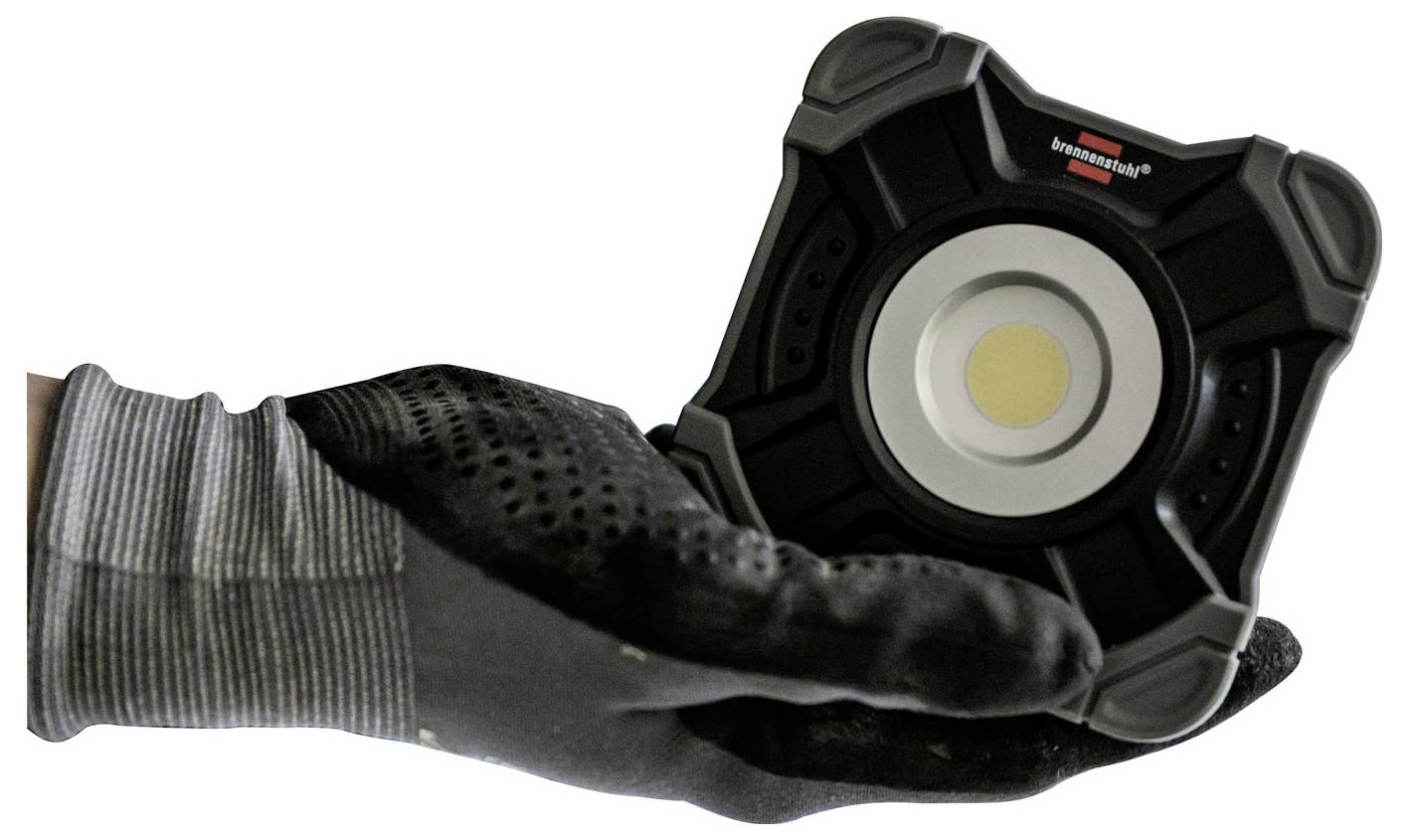 Hand hält eine kleine, quadratische LED-Arbeitsleuchte mit schwarzem Gehäuse. Die Leuchte ist tragbar und robust.