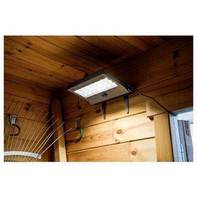LED-Sicherheitsleuchte, die unter einem Holzdachüberstand montiert ist und den Wandbereich und den Eingangstürbereich im Freien beleuchtet.