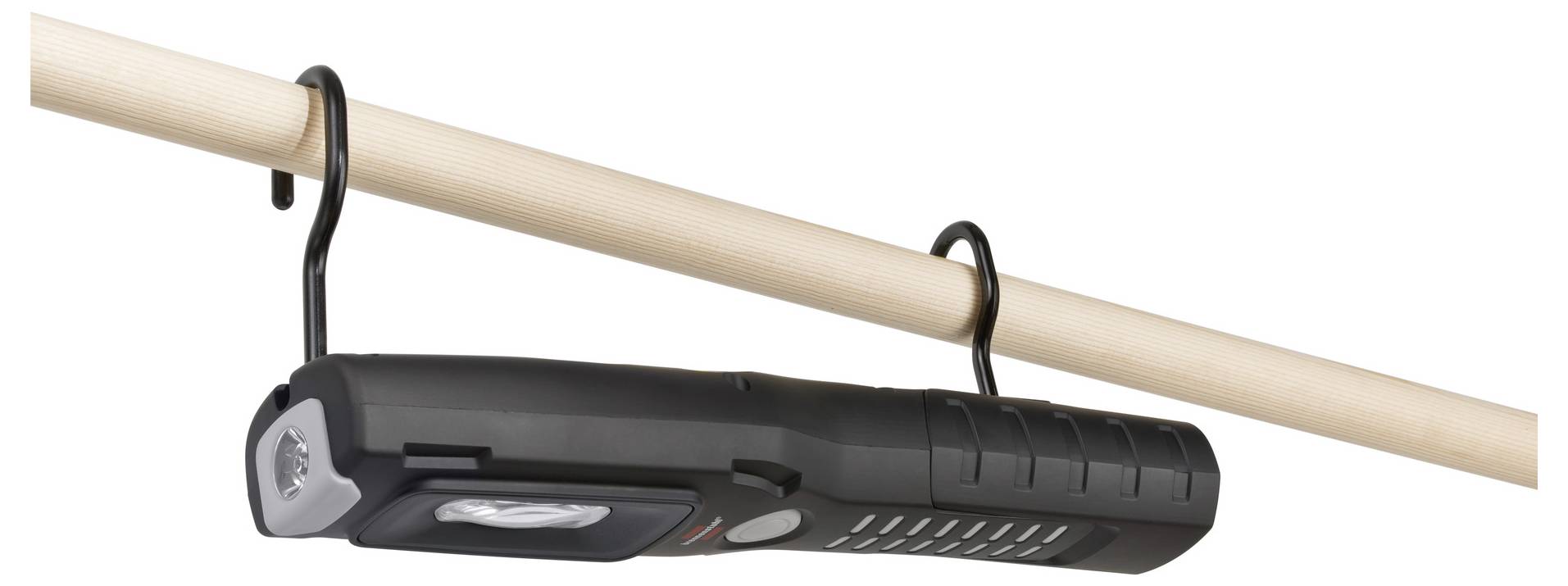 Schwarze Taschenlampe oder Laterne, die von zwei Haken an einer Holzstange hängt, mit einer Handkurbel an einem Ende.