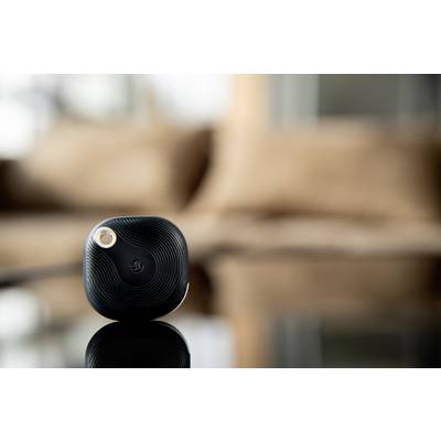 Ein kleiner, schwarzer, quadratischer Bluetooth-Tracker liegt auf einer glänzenden Oberfläche, unscharfer Hintergrund.