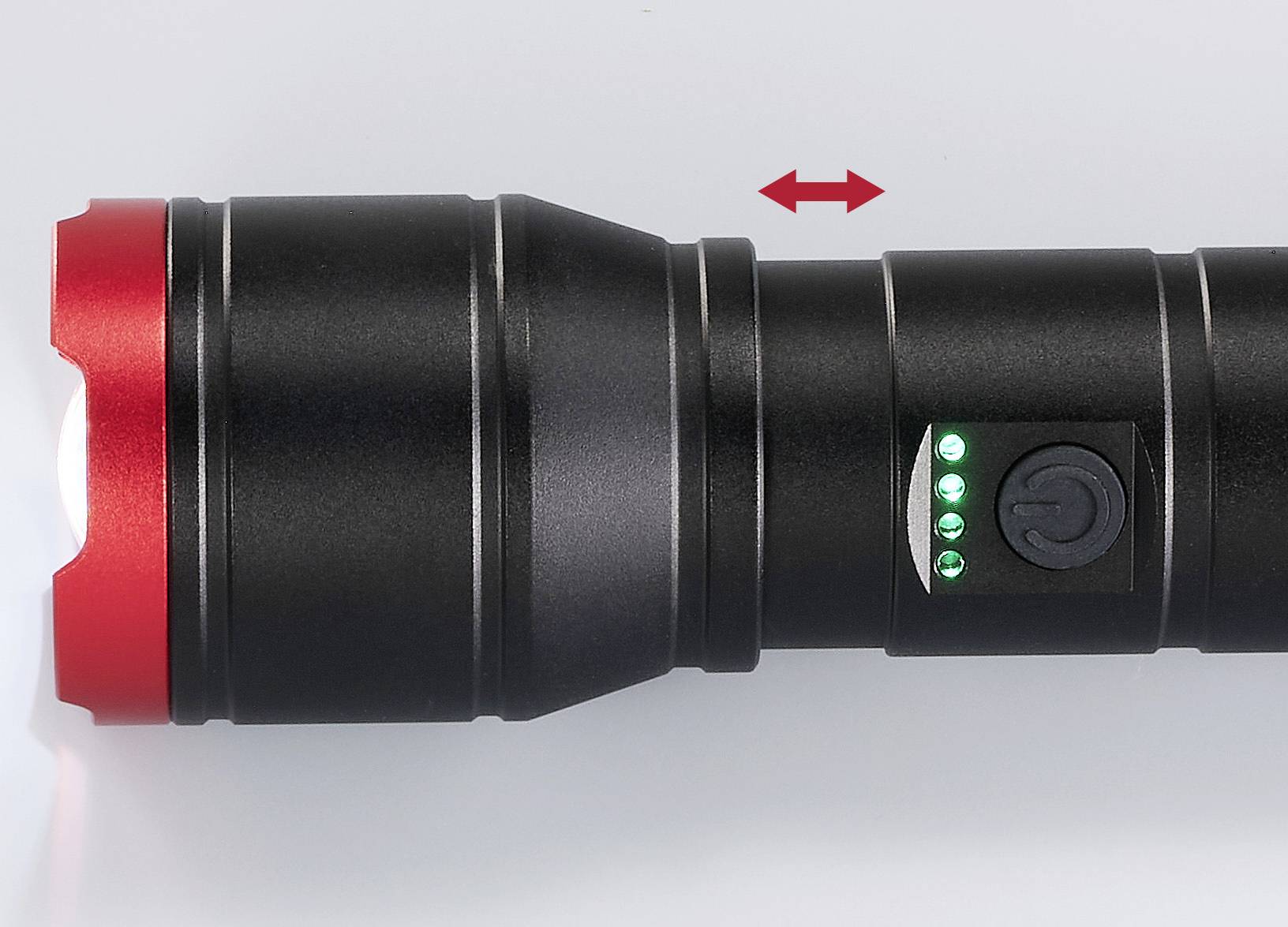 Schwarze Taschenlampe mit roter Kante zeigt grüne Ladeanzeigen. Ein Pfeil zeigt horizontale Bewegungsmöglichkeit an.