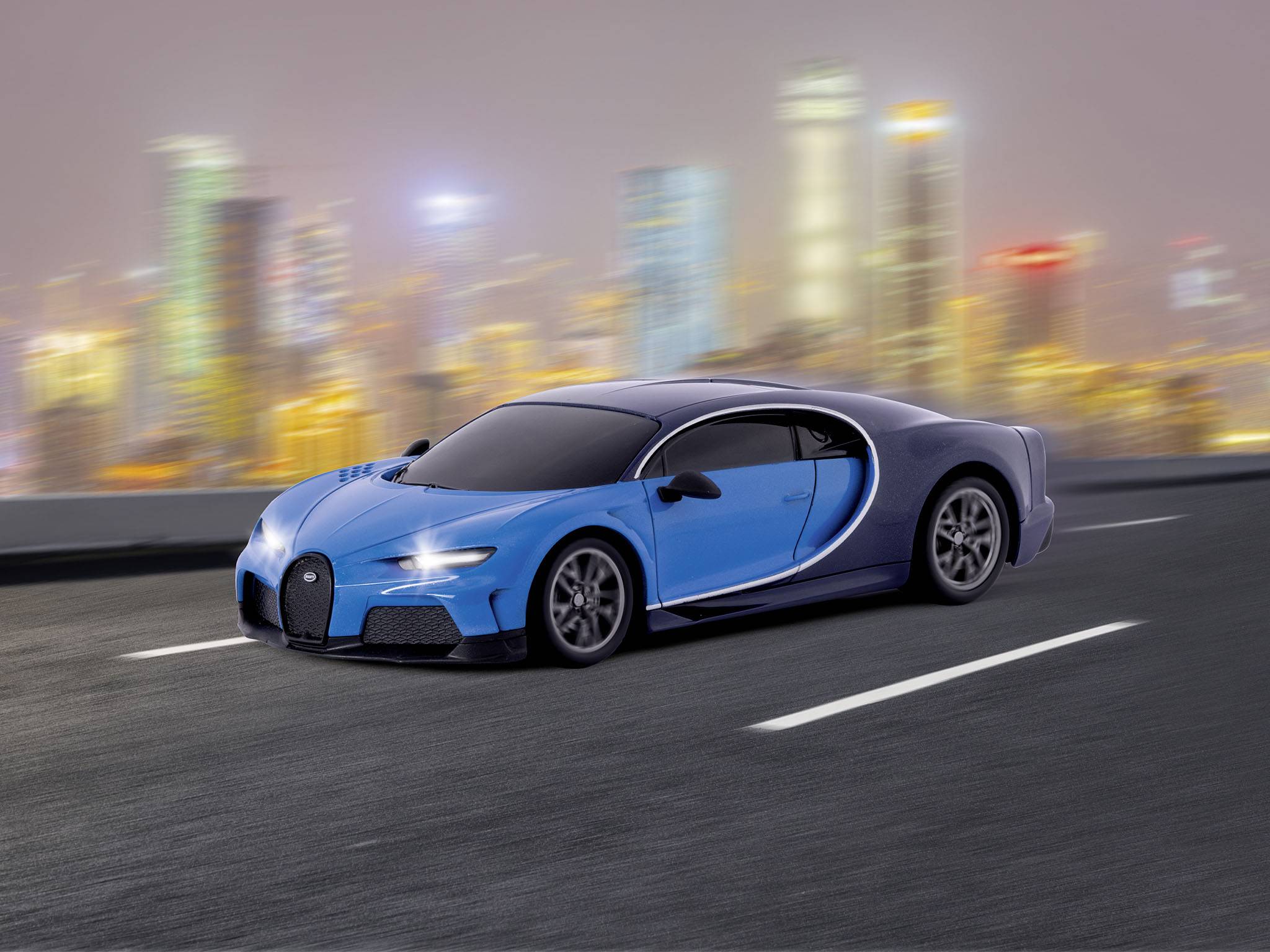 Ein blauer Sportwagen fährt auf einer leeren Stadtautobahn bei Nacht, mit verschwommener Skyline und beleuchteten Gebäuden im Hintergrund.