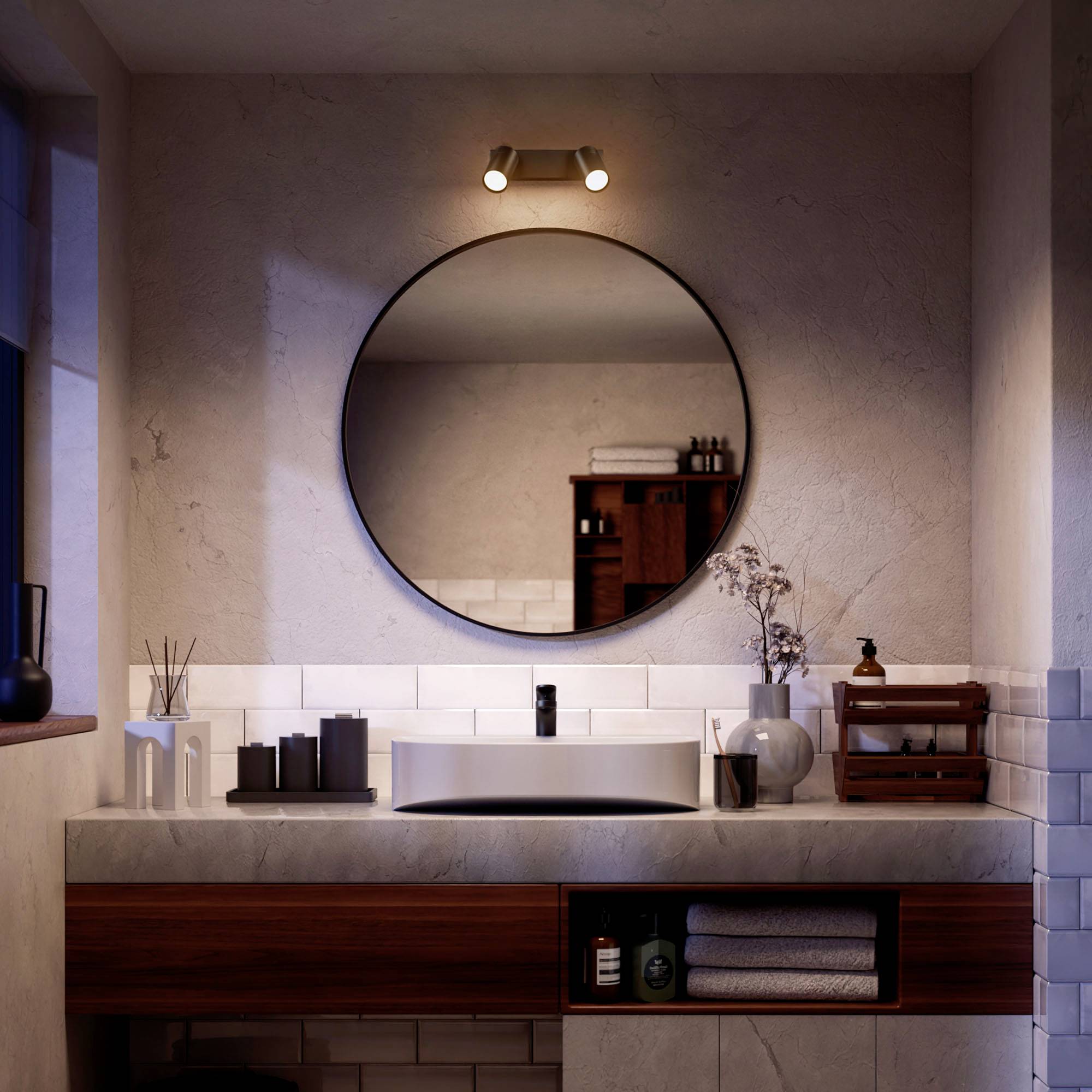 Modernes Badezimmer mit rundem Spiegel, Holzwaschtisch und minimalistischen Dekorelementen. Dezente Beleuchtung schafft eine gemütliche Atmosphäre.