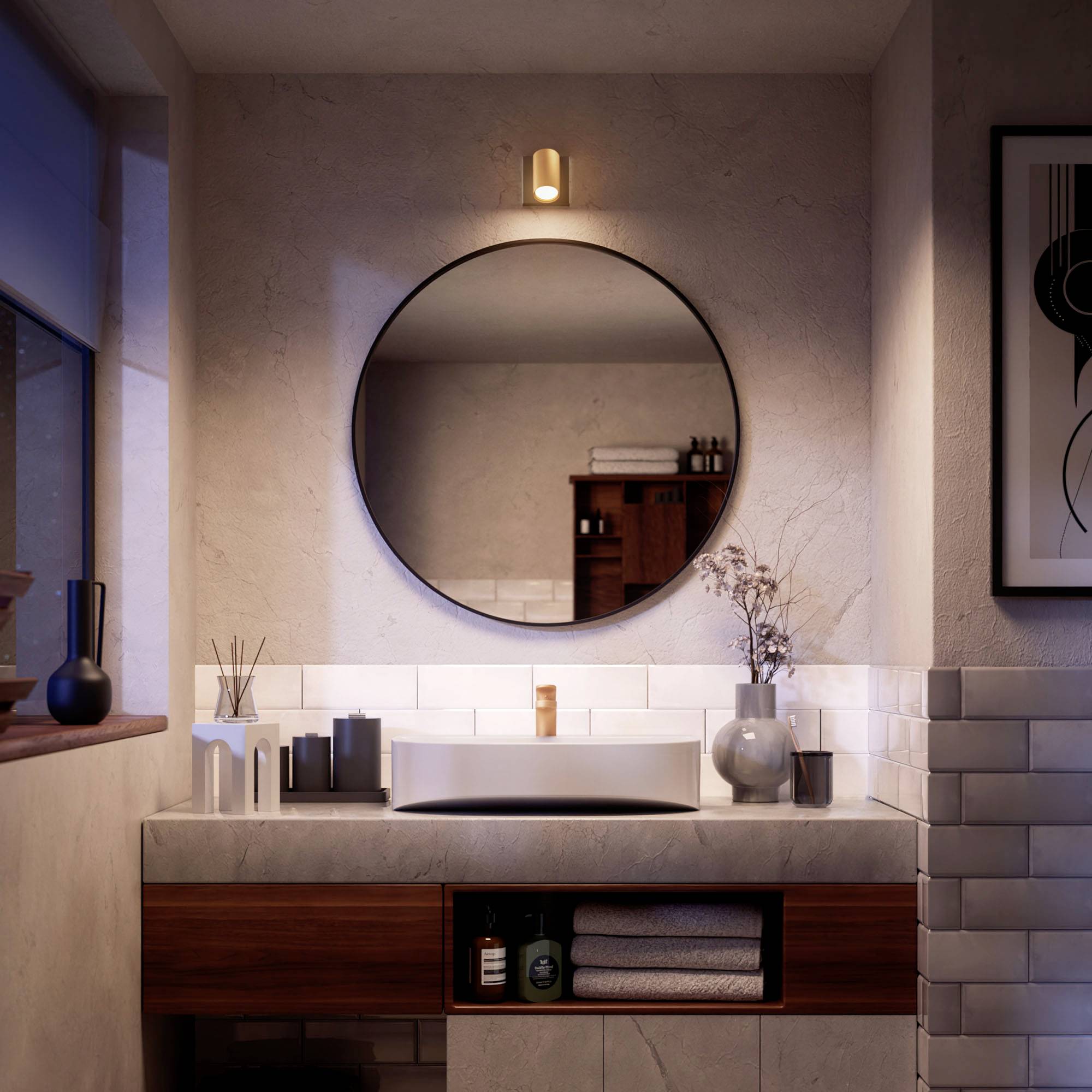 Modernes Badezimmer mit runder Spiegelbeleuchtung. Holzwaschtisch, weiße Fliesen, Pflanzenakzente und Kunstwerk an der Wand.