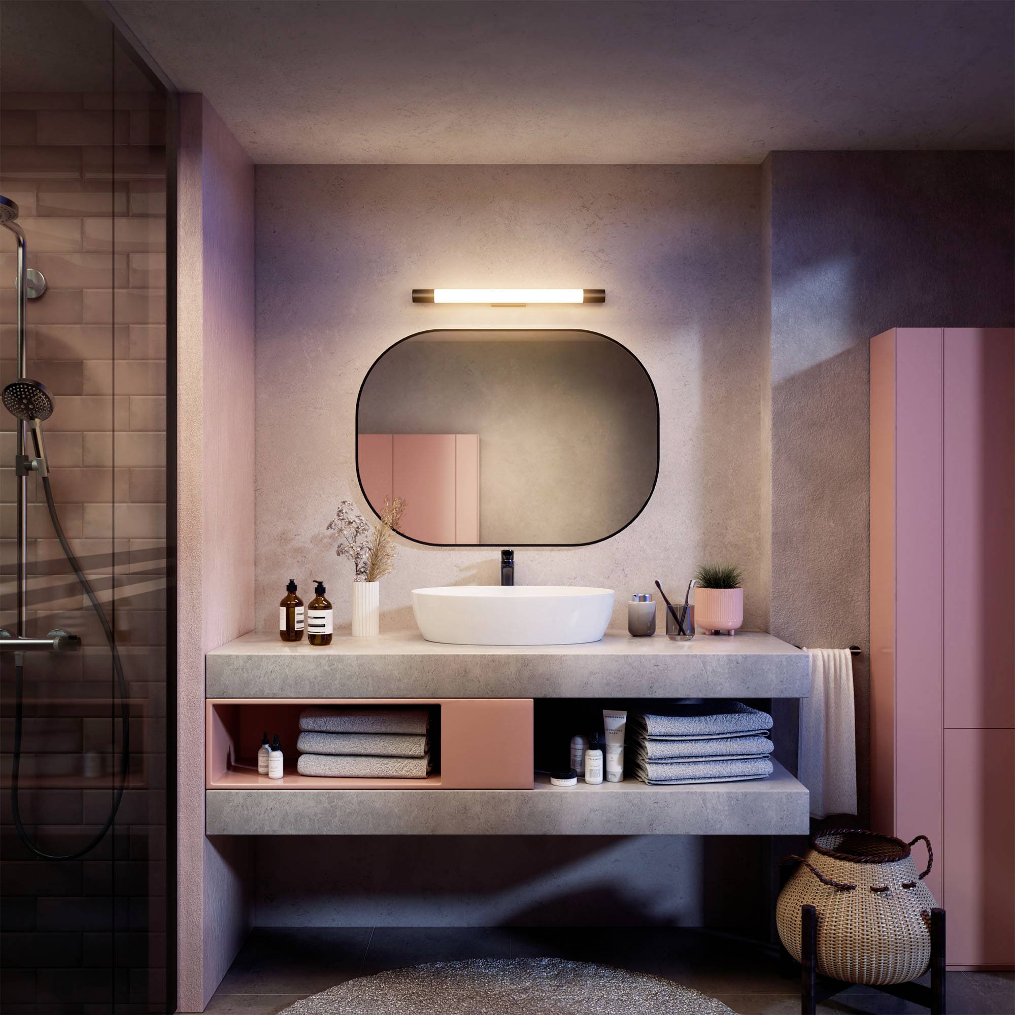 Ein modernes Badezimmer mit rosa Akzenten, einer beleuchteten Spiegel, einem Waschbecken mit Pflegeprodukten und einem Duschbereich.