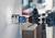 Eine Bohrmaschine erstellt ein kreisförmiges Loch in einer weißen Wand. Ein Lochsägeaufsatz ist an der Bohrmaschine befestigt.