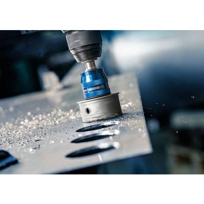Eine Bohrmaschine durchbohrt ein Metallblech, Metallspäne fliegen. Nahaufnahme des Arbeitsprozesses in einer Werkstattumgebung.