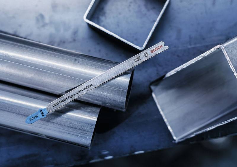Metallsägeblatt liegt auf gestapelten Stahlrohren und Profilen. Markenname 'Bosch' sichtbar auf dem Sägeblatt. Vielseitigkeit im Metallzuschnitt.
