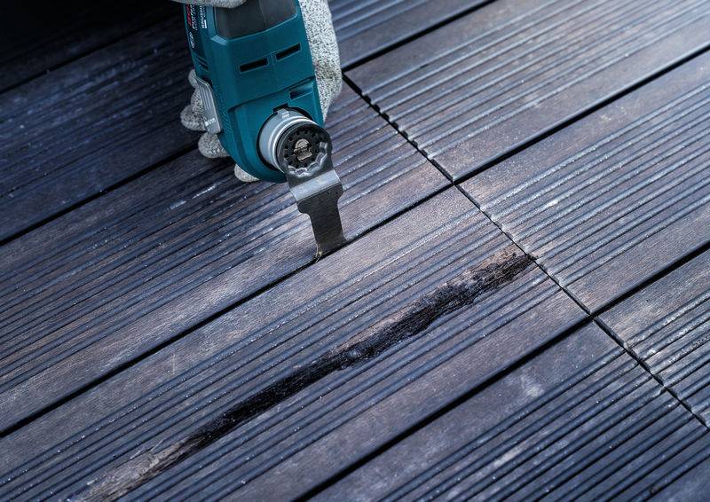 Ein elektrisches Werkzeug schneidet in ein beschädigtes Holzdeck.