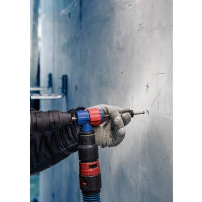 Eine Person in Arbeitshandschuhen bohrt mit einem Bohrer ein Loch in eine Wand. Fokus auf der Hand und dem Bohrer.