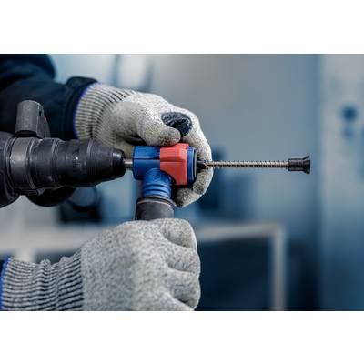 Eine Person in Handschuhen hält ein rot-blaues Werkzeug, das eine Schraube in einen Bohrer dreht. Der Fokus liegt auf der Handhabung.