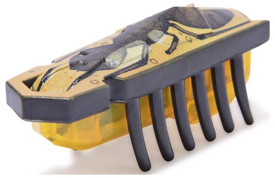 Ein kleines, sechseckiges, bürstenartiges Roboter-Spielzeug mit schwarzen Beinchen und einem gelb-schwarz gestreiften Muster oben.