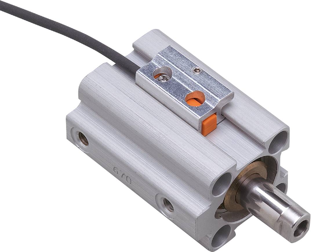 Zylinderförmiges Metallbauteil mit rechteckiger Halterung und Anschlusskabel, möglicherweise Teil eines mechanischen oder elektronischen Geräts.