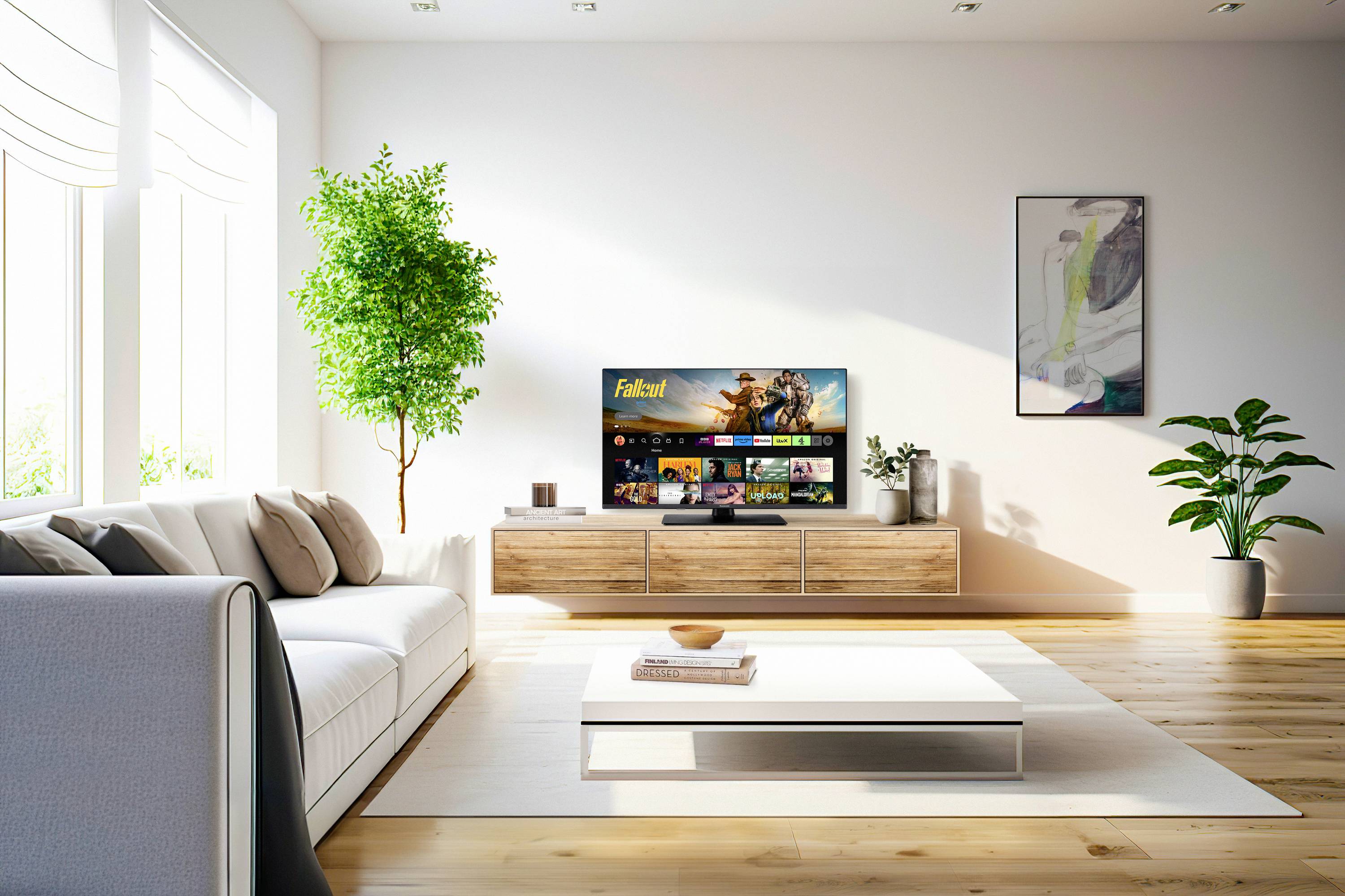 Helles Wohnzimmer mit modernen Möbeln: graues Sofa, Holzschrank, Fernseher zeigt 'Fallout'. Pflanzen dekorieren den Raum.