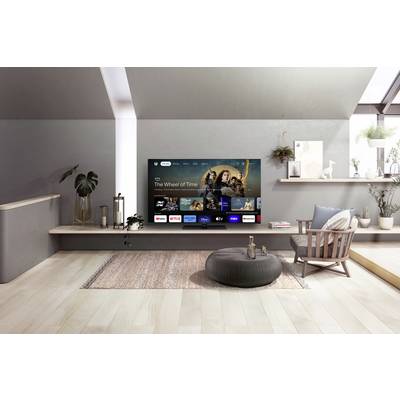 Moderne Wohnzimmer mit großem Flachbildfernseher an der Wand. Der Fernseher zeigt Streaming-Dienste wie Netflix und Disney+. Elegantes, minimalistisches Design.