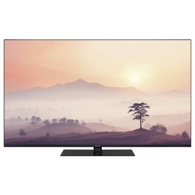 Ein Fernseher zeigt eine Landschaft mit sanften Hügeln und einem Baum im Vordergrund, während die Sonne hinter den Bergen aufgeht.