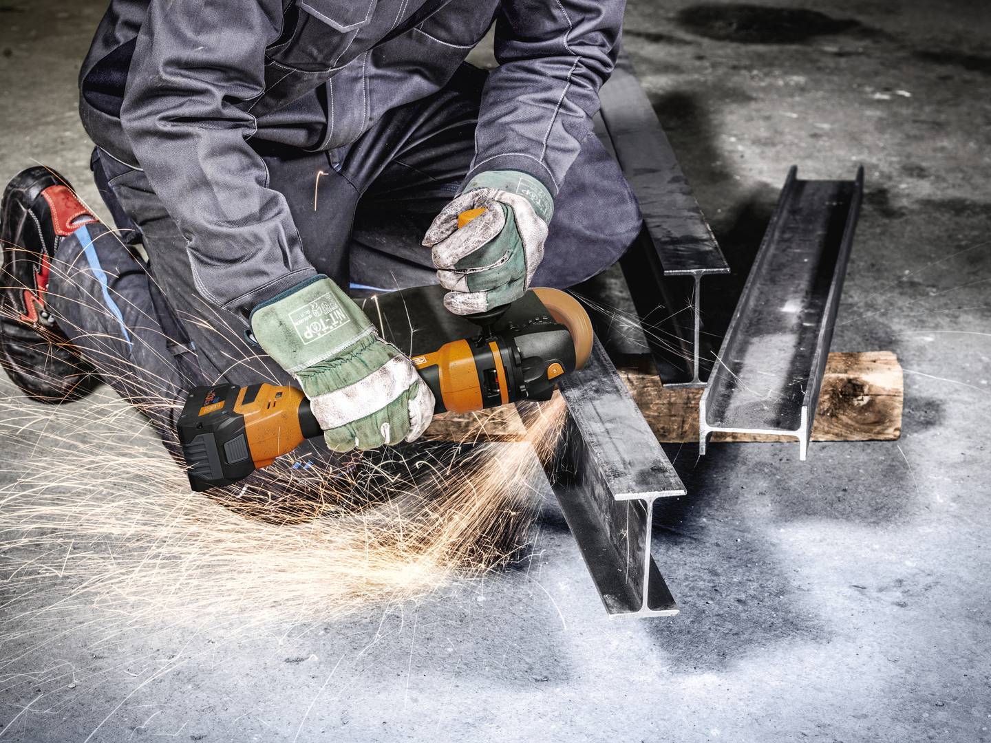 Arbeiter in Schutzkleidung schneidet Metallträger mit Winkelschleifer. Funken fliegen, Arbeitsumgebung industriell.
