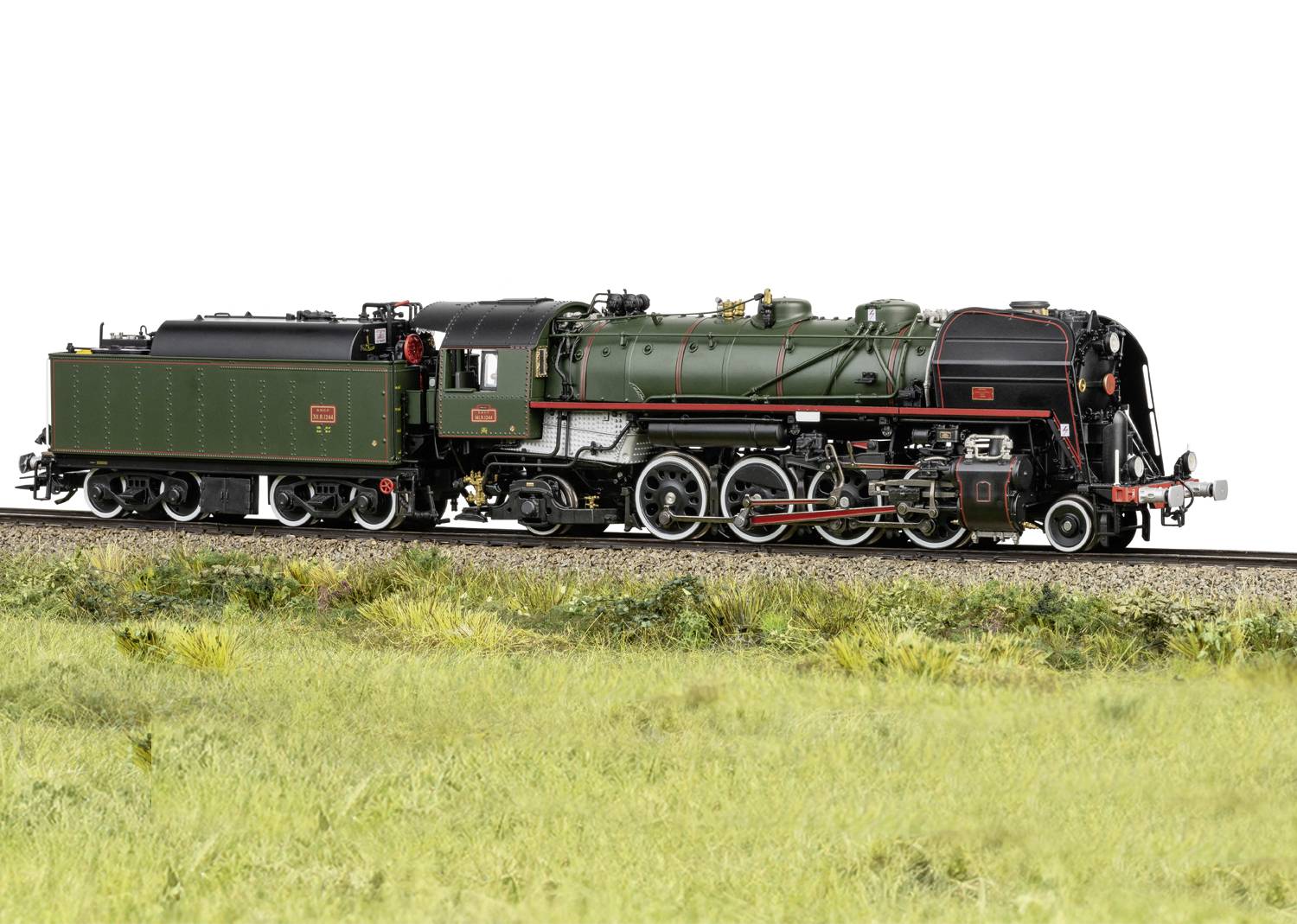 Historische grüne Dampflokomotive auf Eisenbahngleisen mit Wiese im Vordergrund. Lokomotive besitzt schwarze Details und rote Markierungen.