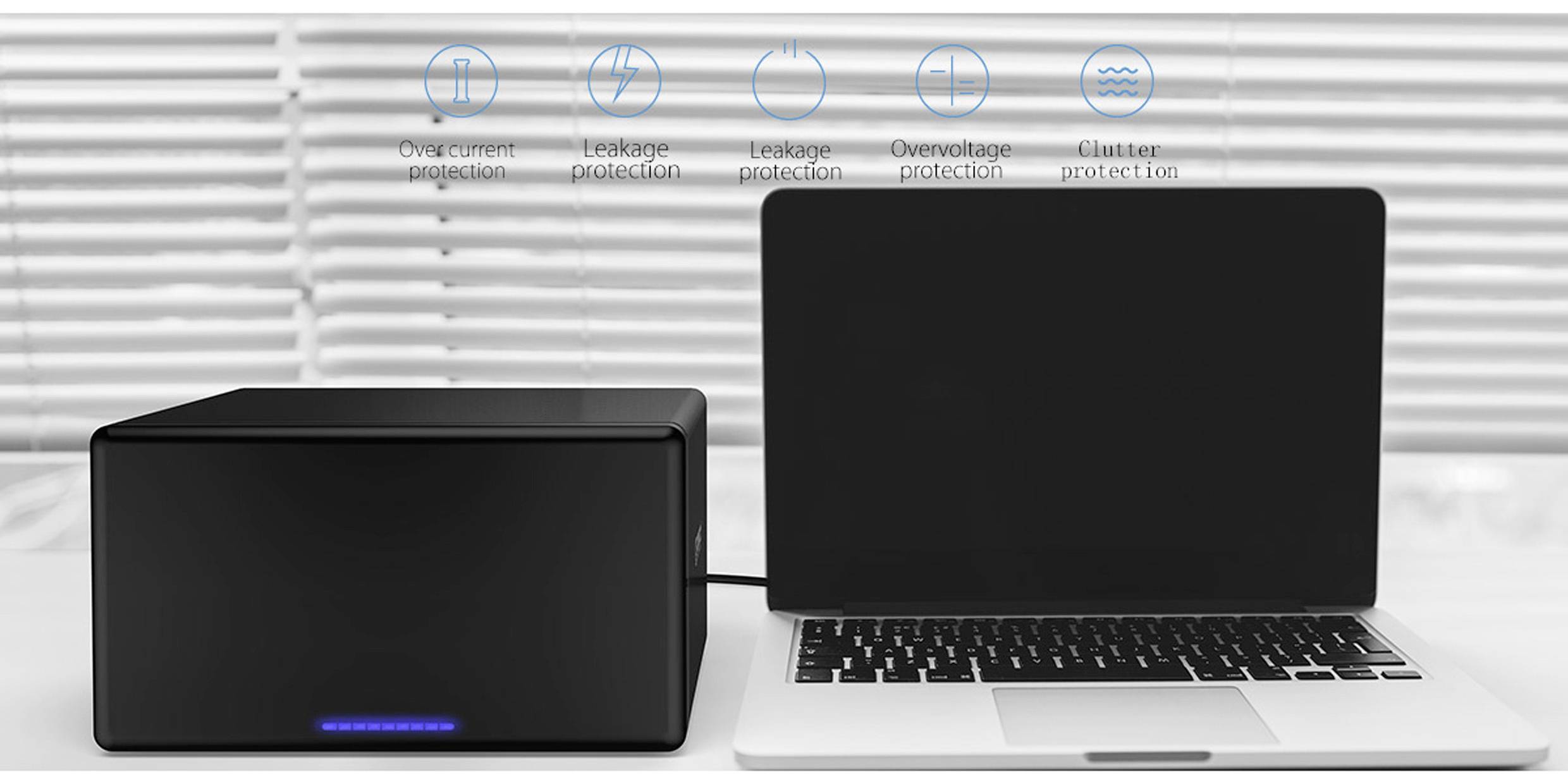 'Schwarze Box neben einem Laptop auf einem Tisch, mit Symbolen für Überstrom-, Leckage-, Überspannungs- und Blitzeinschlag-Schutz.'