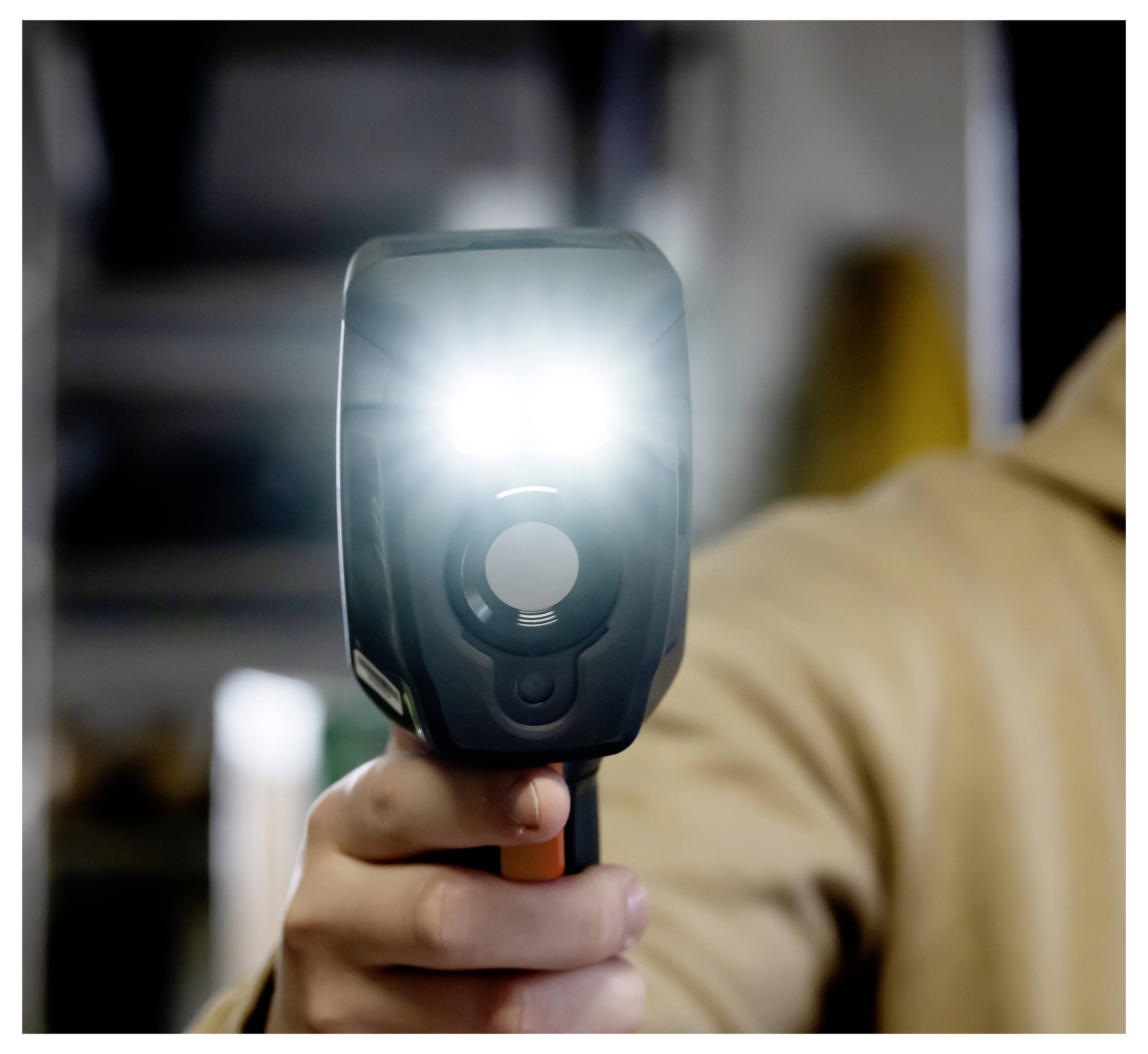 Person hält ein tragbares Geschwindigkeitsmessgerät auf die Kamera gerichtet, mit einem hellen Blitz vom Gerät.