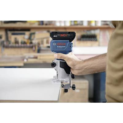 Eine Person, die eine Bosch Professional Oberfräse hält und sie fest gegen ein Holzstück in einer Werkstattumgebung drückt, konzentriert auf präzises Holzarbeiten.