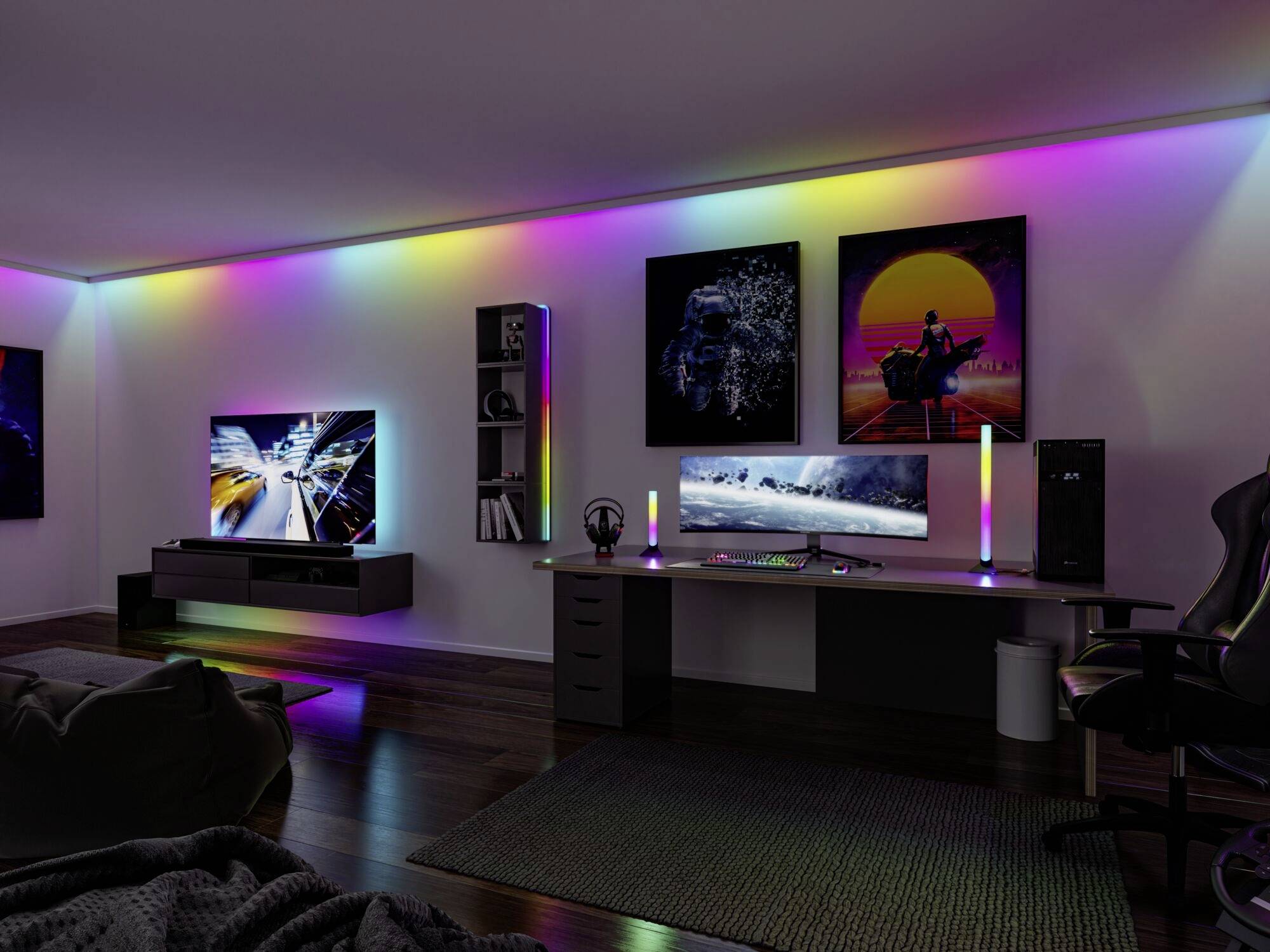 Ein moderner Gaming-Raum mit RGB-Beleuchtung, zwei Monitoren auf einem Schreibtisch, einer großen Couch und stilvollen Wandbildern.