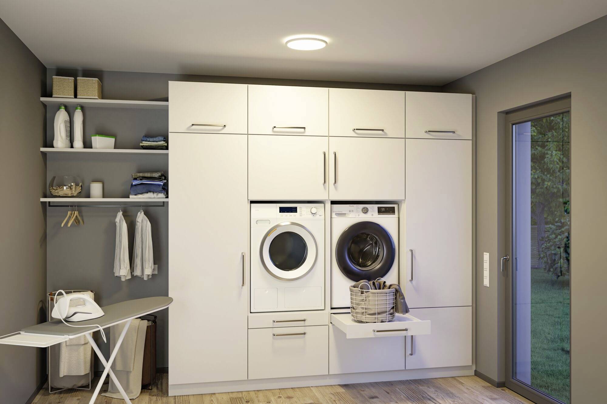 Hauswirtschaftsraum mit moderner Waschmaschine und Trockner nebeneinander, umgeben von grauen Schränken. Rechts eine Glastür nach draußen.