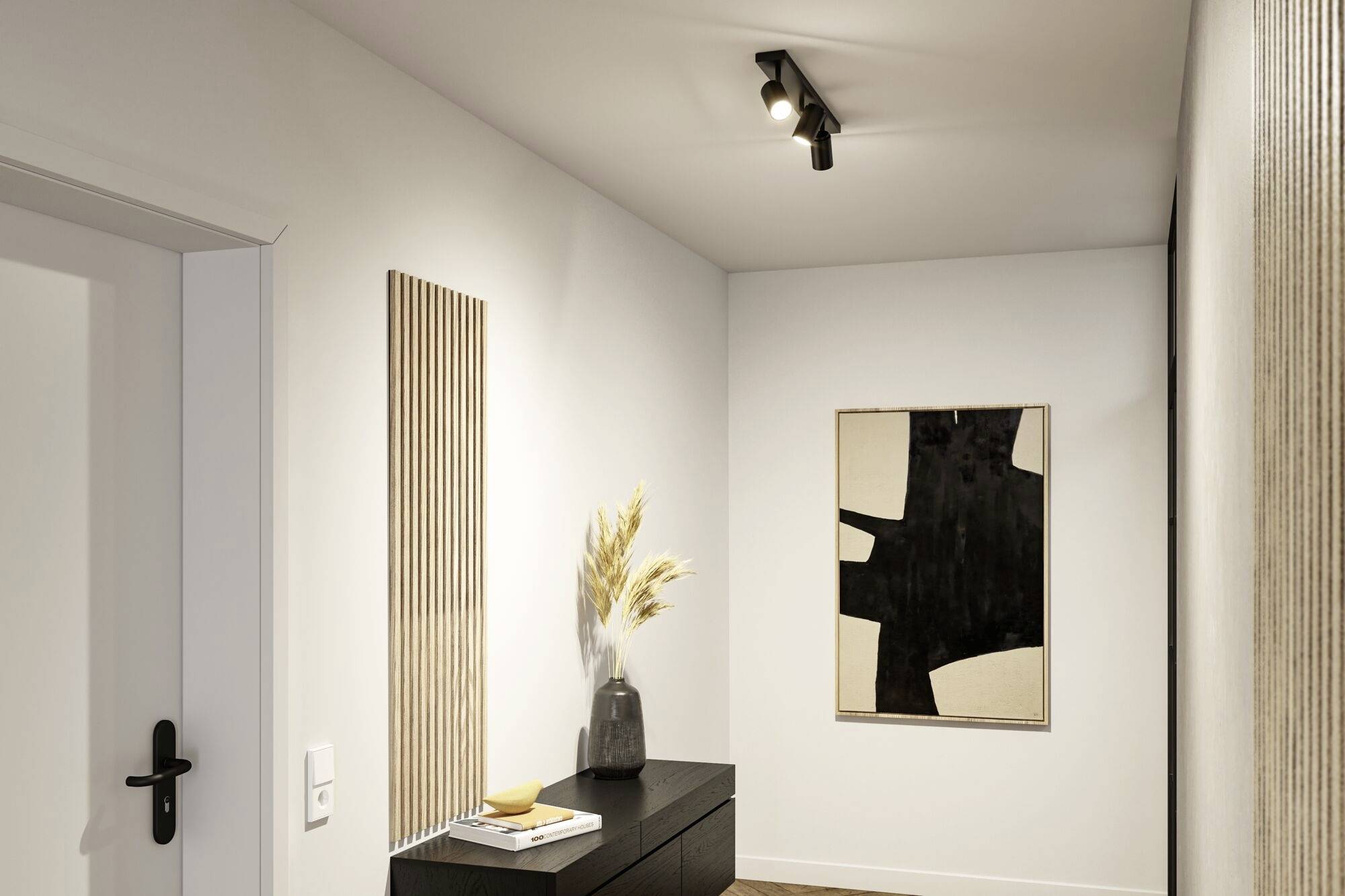 Ein minimalistischer Flur mit einem schwarzen Sideboard, darauf eine Vase mit Gräsern. An der Wand hängt moderne Kunst.