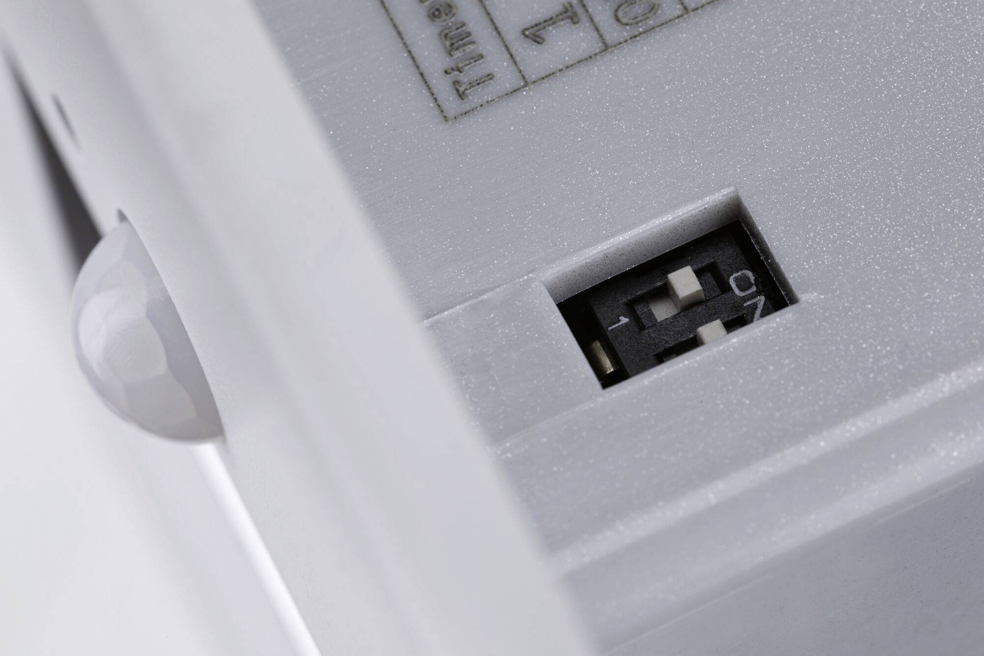 Nahaufnahme eines elektrischen Schalters mit zwei kleinen Kippschaltern und einem Infrarotsensor an der Seite.