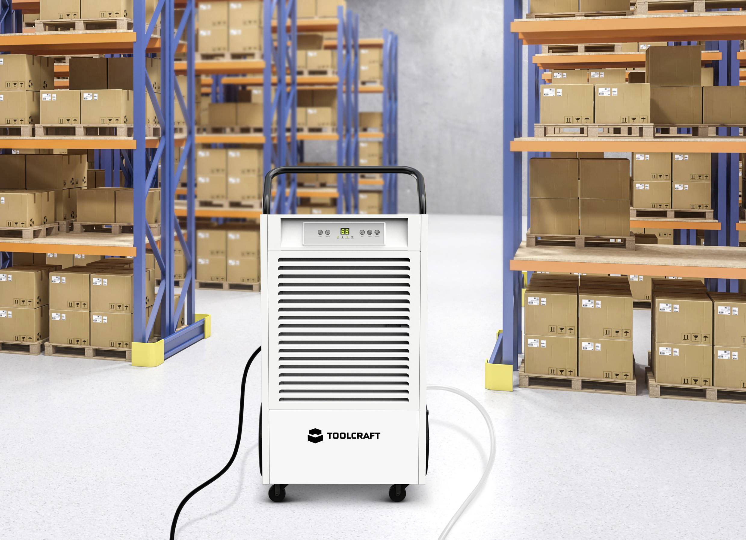 Ein Luftentfeuchter im Lager mit Regalen voller Kartons; das Gerät steht zentral im Vordergrund und ist weiß mit einem schwarzen Handgriff.